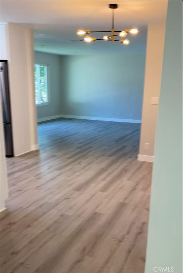 empty room with an inviting chandelier and wood-type flooring