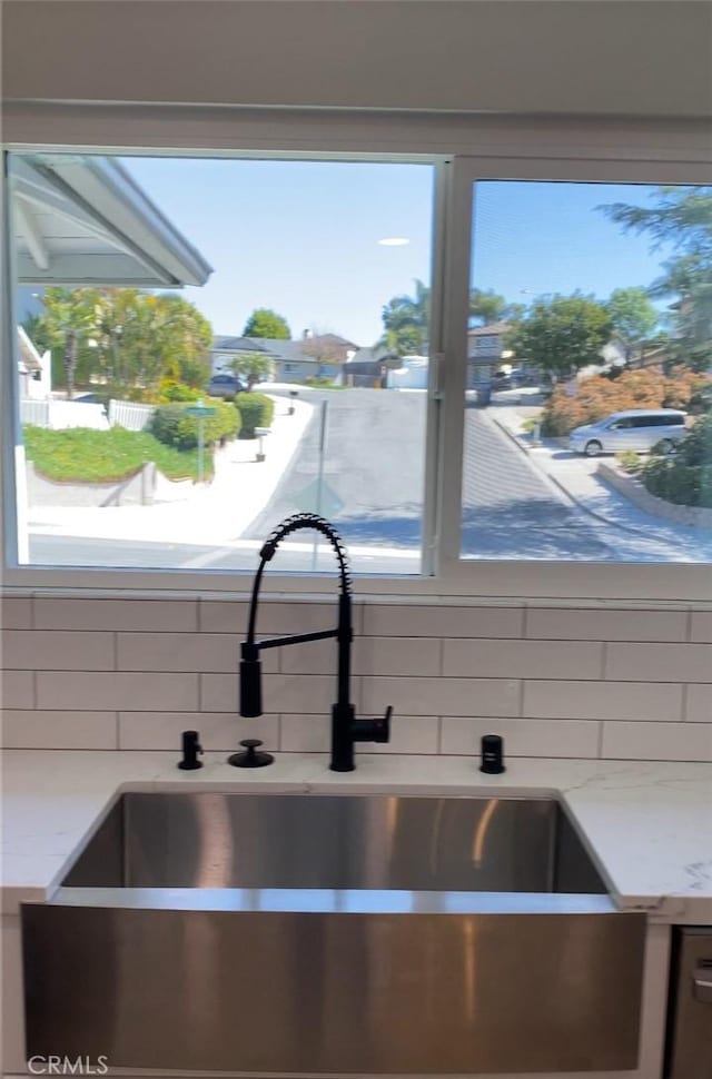 interior details with sink, backsplash, and light stone countertops