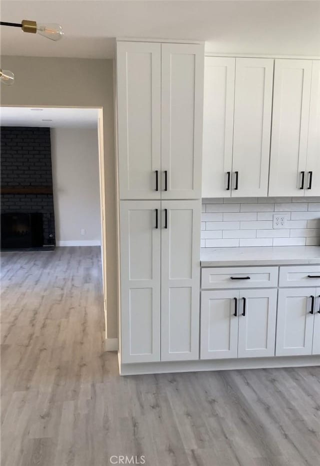 interior details with decorative backsplash, hardwood / wood-style flooring, and a fireplace