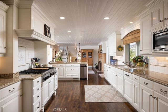 kitchen with hanging light fixtures, white cabinets, kitchen peninsula, and stainless steel appliances