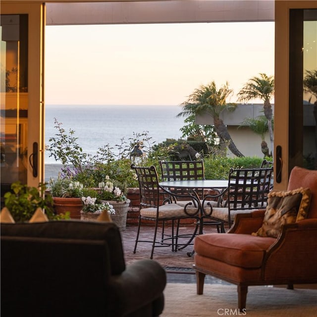 balcony at dusk featuring a water view