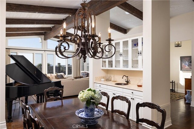 dining space with vaulted ceiling with beams, dark hardwood / wood-style floors, sink, and an inviting chandelier