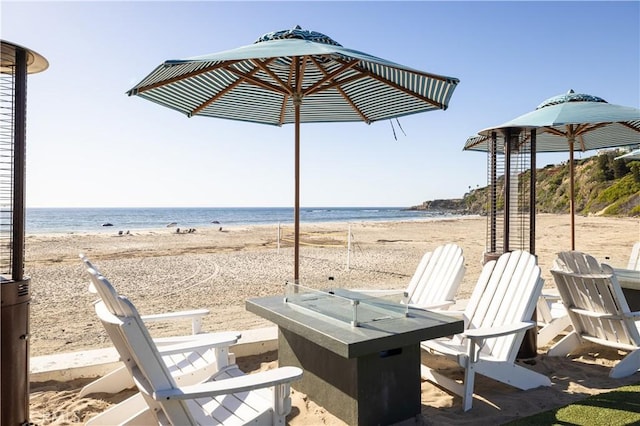 view of patio with a beach view, an outdoor fire pit, and a water view