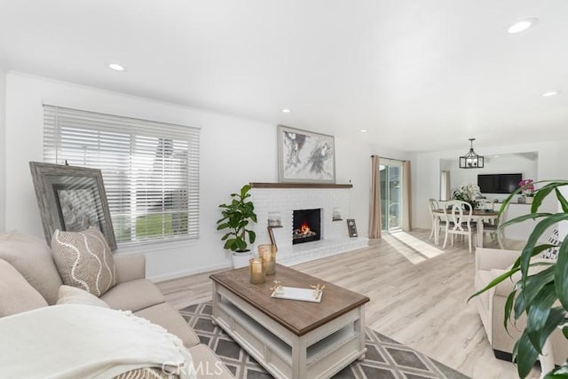 living room with light hardwood / wood-style flooring, a chandelier, and a fireplace