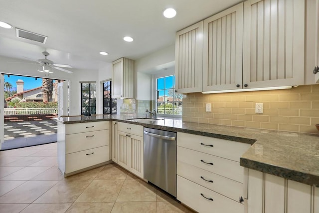 kitchen with stainless steel dishwasher, kitchen peninsula, light tile patterned flooring, sink, and cream cabinets