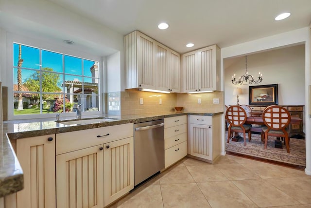 kitchen featuring stainless steel dishwasher, cream cabinetry, sink, and decorative light fixtures