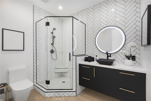 bathroom featuring toilet, vanity, tile walls, and walk in shower