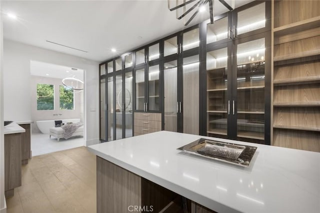 walk in closet with light hardwood / wood-style flooring and a chandelier