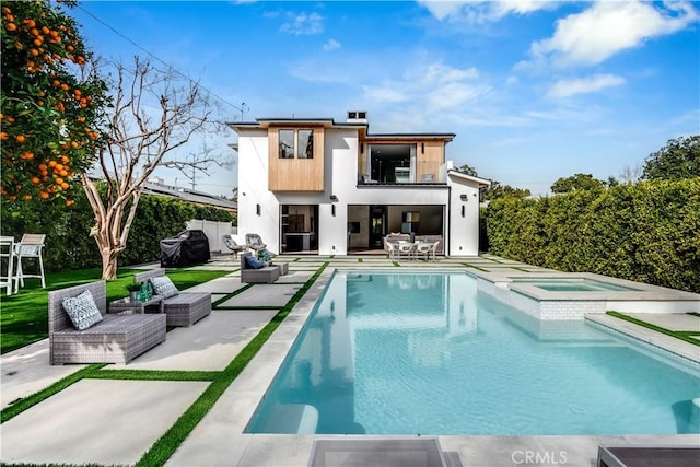 rear view of property featuring a pool with hot tub, a balcony, and a patio