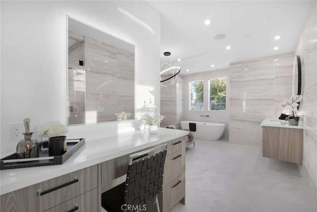 bathroom with tile walls, a washtub, and vanity