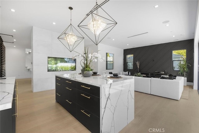 kitchen with decorative light fixtures, an inviting chandelier, light stone countertops, and a spacious island