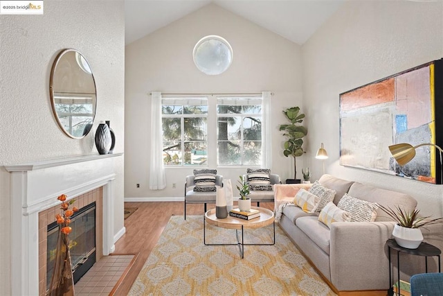 living room with a fireplace, vaulted ceiling, and light hardwood / wood-style flooring