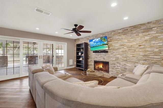 living room featuring ceiling fan, a stone fireplace, and hardwood / wood-style floors