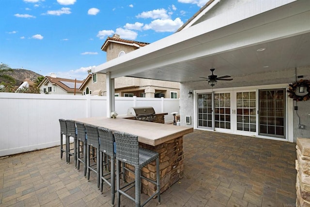 view of patio with ceiling fan, an outdoor bar, a grill, and area for grilling