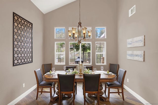 dining area with high vaulted ceiling, wood-type flooring, and a notable chandelier