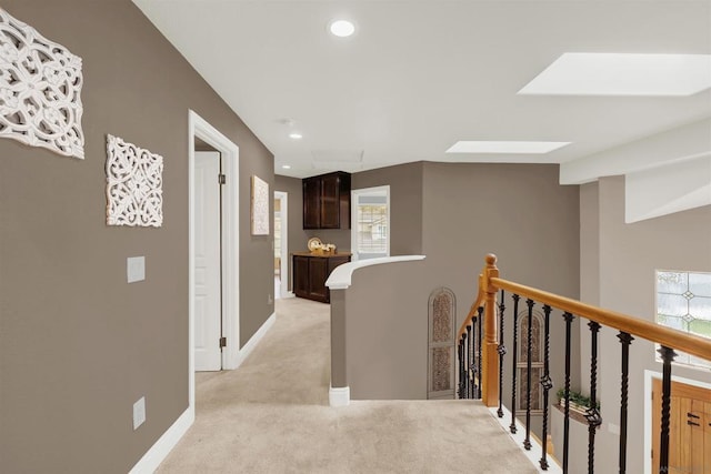 hallway with light colored carpet and a skylight