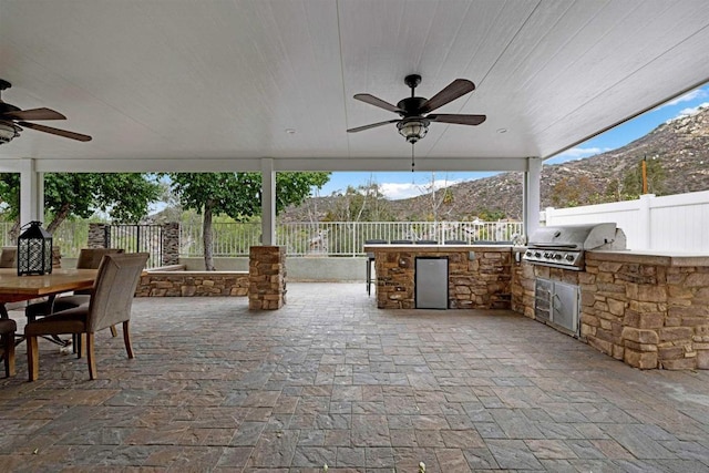 view of patio / terrace featuring a mountain view, ceiling fan, exterior kitchen, and area for grilling