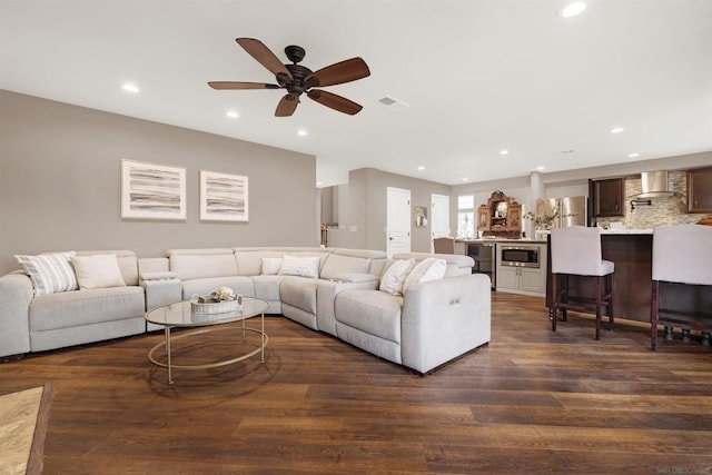 living room featuring ceiling fan and dark hardwood / wood-style flooring