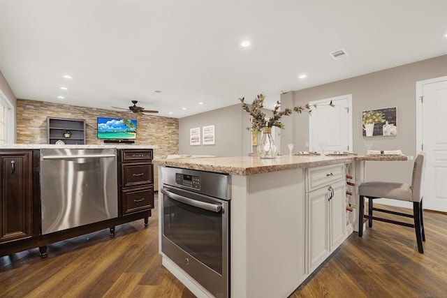 kitchen featuring ceiling fan, dark brown cabinetry, appliances with stainless steel finishes, and a center island