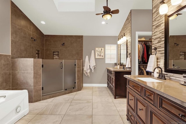 bathroom with ceiling fan, vaulted ceiling with skylight, vanity, and independent shower and bath