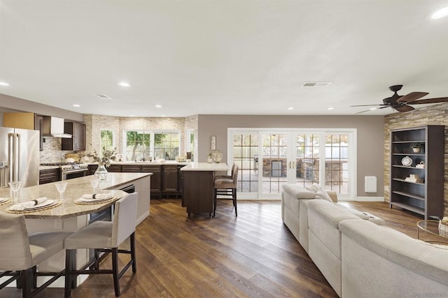 kitchen featuring a kitchen bar, appliances with stainless steel finishes, dark brown cabinets, and a kitchen island