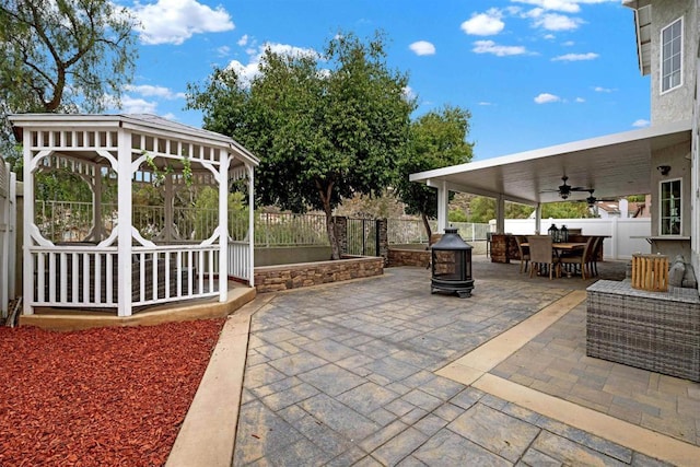 view of patio with ceiling fan, a gazebo, and a fire pit