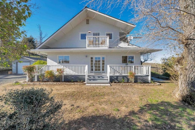 rear view of property with a balcony, a garage, an outbuilding, and a lawn