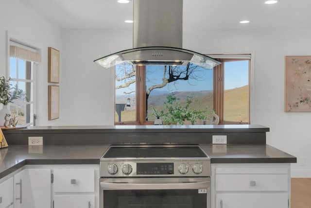 kitchen with island exhaust hood, stainless steel electric range oven, plenty of natural light, and white cabinets