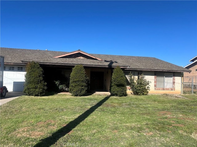 single story home featuring a garage, roof with shingles, and a front yard