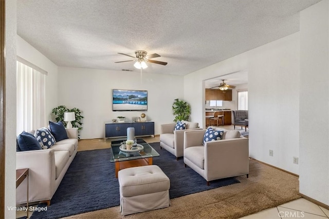 carpeted living area with a textured ceiling and a ceiling fan