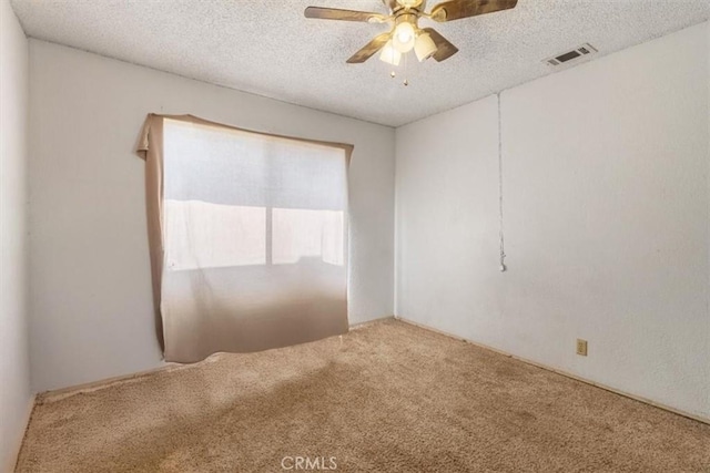 carpeted empty room featuring a textured ceiling, visible vents, and a ceiling fan