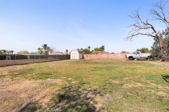 view of yard with fence, a storage unit, and an outbuilding