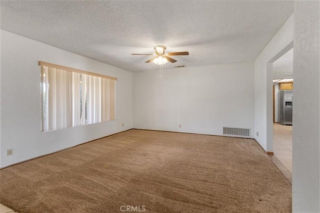 unfurnished room featuring ceiling fan, visible vents, a textured ceiling, and light colored carpet