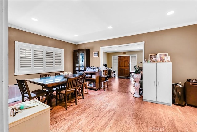 dining space with light wood-type flooring and crown molding