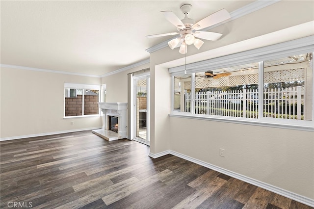 unfurnished living room featuring a premium fireplace, ornamental molding, dark hardwood / wood-style floors, and ceiling fan