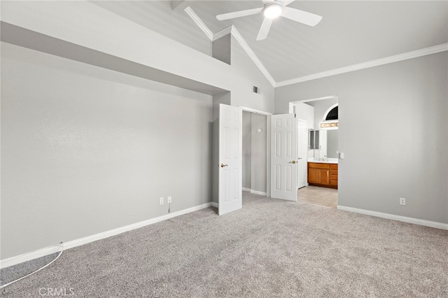 unfurnished bedroom with ceiling fan, light colored carpet, ensuite bath, crown molding, and high vaulted ceiling