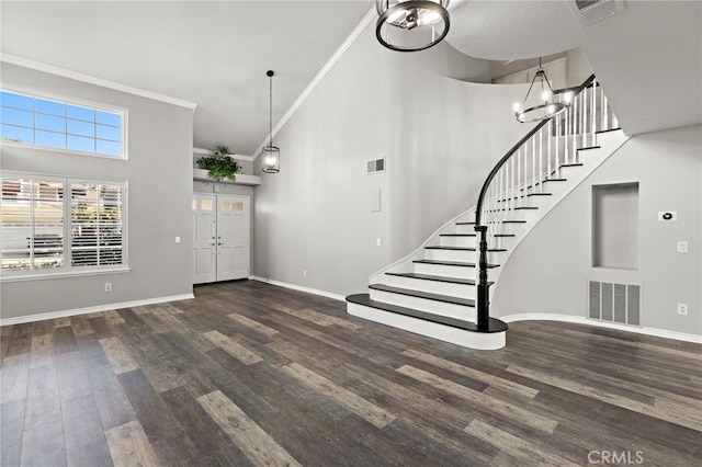 entrance foyer featuring dark hardwood / wood-style flooring, crown molding, a towering ceiling, and a notable chandelier