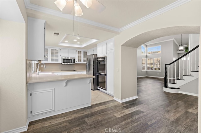 kitchen featuring pendant lighting, white cabinetry, stainless steel appliances, sink, and kitchen peninsula