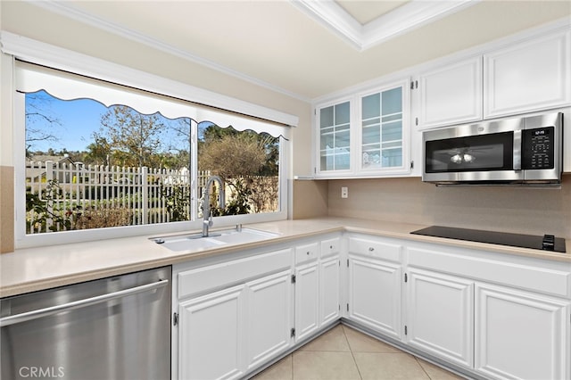 kitchen featuring white cabinets, stainless steel appliances, sink, ornamental molding, and light tile patterned floors