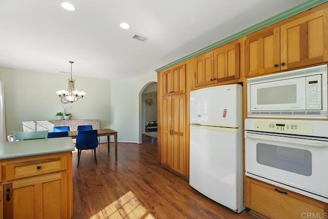 kitchen with white appliances, dark wood-type flooring, a notable chandelier, and decorative light fixtures