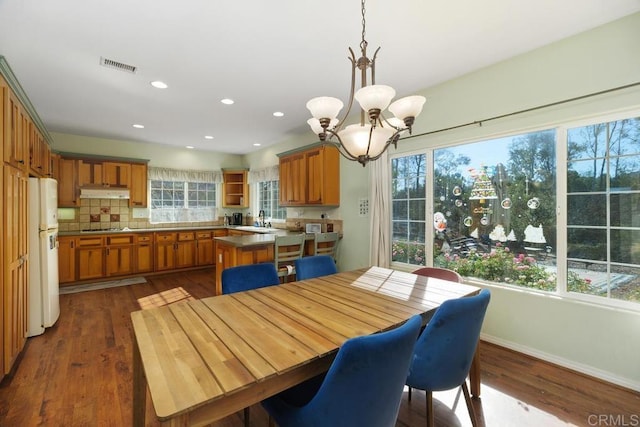 dining area featuring sink, an inviting chandelier, and dark hardwood / wood-style flooring