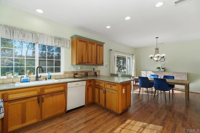 kitchen with dishwasher, dark wood-type flooring, pendant lighting, sink, and kitchen peninsula