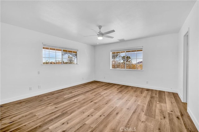 spare room with ceiling fan, a wealth of natural light, and light hardwood / wood-style floors