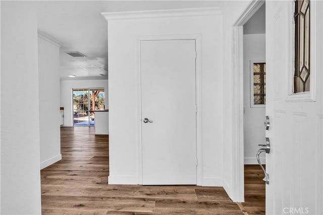 hall with wood-type flooring and ornamental molding