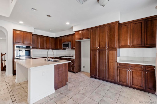 kitchen featuring sink, light tile patterned floors, a kitchen island with sink, and appliances with stainless steel finishes