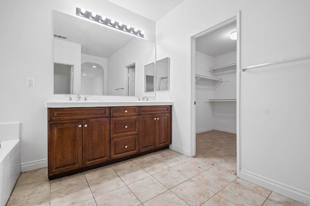 bathroom with a relaxing tiled tub, tile patterned floors, and vanity