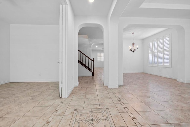 tiled spare room with an inviting chandelier