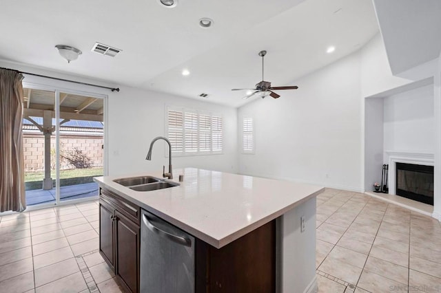 kitchen with sink, an island with sink, stainless steel dishwasher, and light tile patterned floors