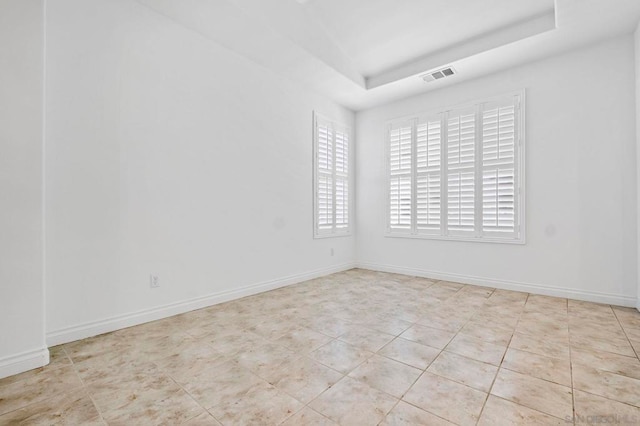 empty room featuring light tile patterned flooring and a tray ceiling