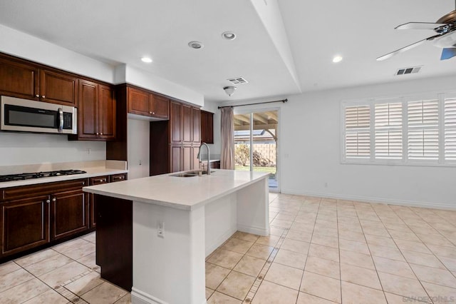 kitchen with a center island with sink, gas stovetop, light tile patterned flooring, ceiling fan, and sink